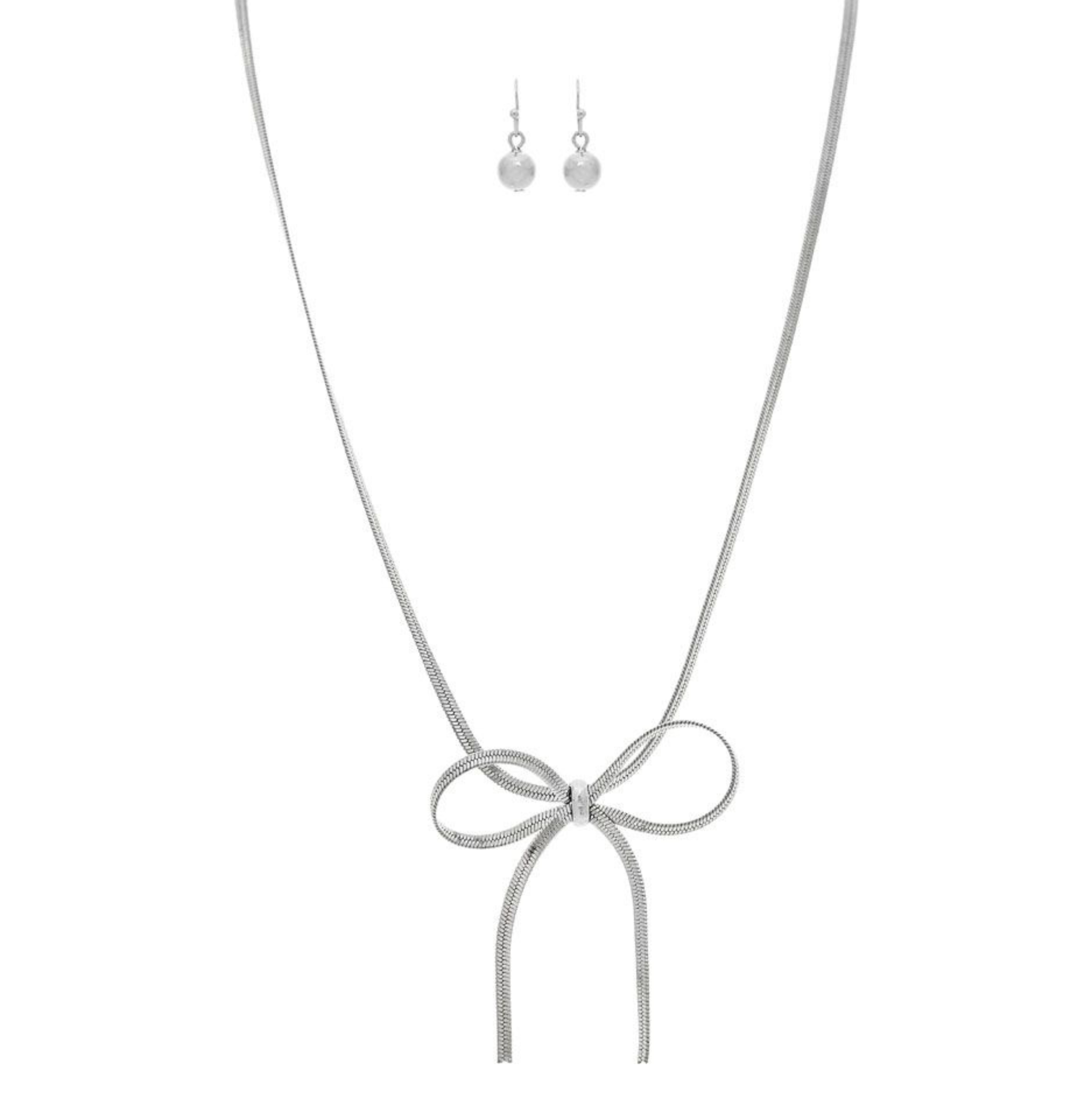 The A-Train Silver Herringbone Chain Bow Tie Necklace Set features a silver bow pendant and matching drop earrings with round beads, elegantly displayed on a white background.