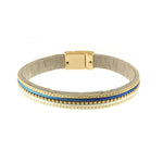 The Origin Matte Gold, Navy & White Gold Bead Center Magnetic Bracelet features a beige suede band with a matte gold clasp and parallel rows of gold, blue, and turquoise beads—an elegant accessory for any style.