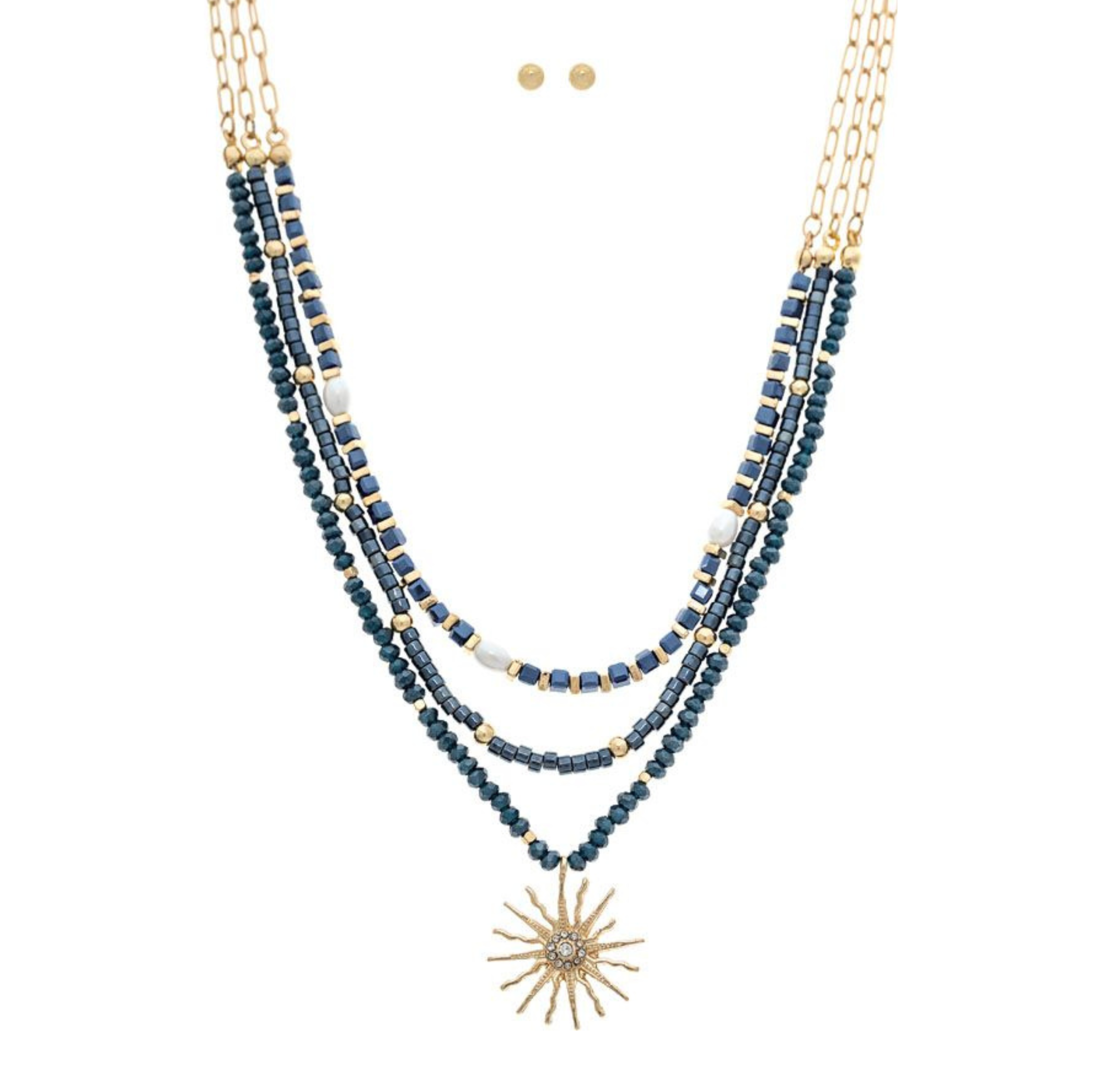 The A-Train Gold Blue Beaded Layer Sunburst Necklace Set features layered gold chains with blue and gold beads, white accents, a sunburst pendant, and matching stud earrings—ideal jewelry for special occasions.