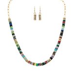 The A-Train Gold Multi Stone Disc Beads Necklace Set features a vibrant necklace with colorful stacked disc beads and gold accents, plus matching dangle earrings with three stacked gold beads for a coordinated style.