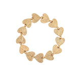 The A-Train Gold Line Etched Hearts Stretch Bracelet features textured gold heart-shaped charms and small beads, crafted from mixed jeweler’s metals for versatile style perfect for any occasion.