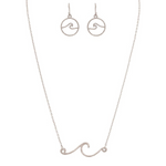 The A-Train Silver Rip Curl Wave Necklace Set includes a delicate necklace with a wave-shaped pendant and matching circular wave earrings, all displayed on a white background.