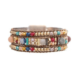 The A-Train Gold Multicolor Bead Cord Woven Bead Magnetic Bracelet features vibrant rows of colorful and gold-tone beads on brown cord, adding a lively accent to any outfit.