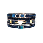 A-Train’s Silver Blue Pearl Crystal XXX Magnetic Bracelet features blue and navy layers, gold accents, and an oval white stone centerpiece—arranged on a white background. A perfect addition to your stylish jewelry collection.