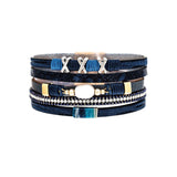 A-Train’s Silver Blue Pearl Crystal XXX Magnetic Bracelet features blue and navy layers, gold accents, and an oval white stone centerpiece—arranged on a white background. A perfect addition to your stylish jewelry collection.