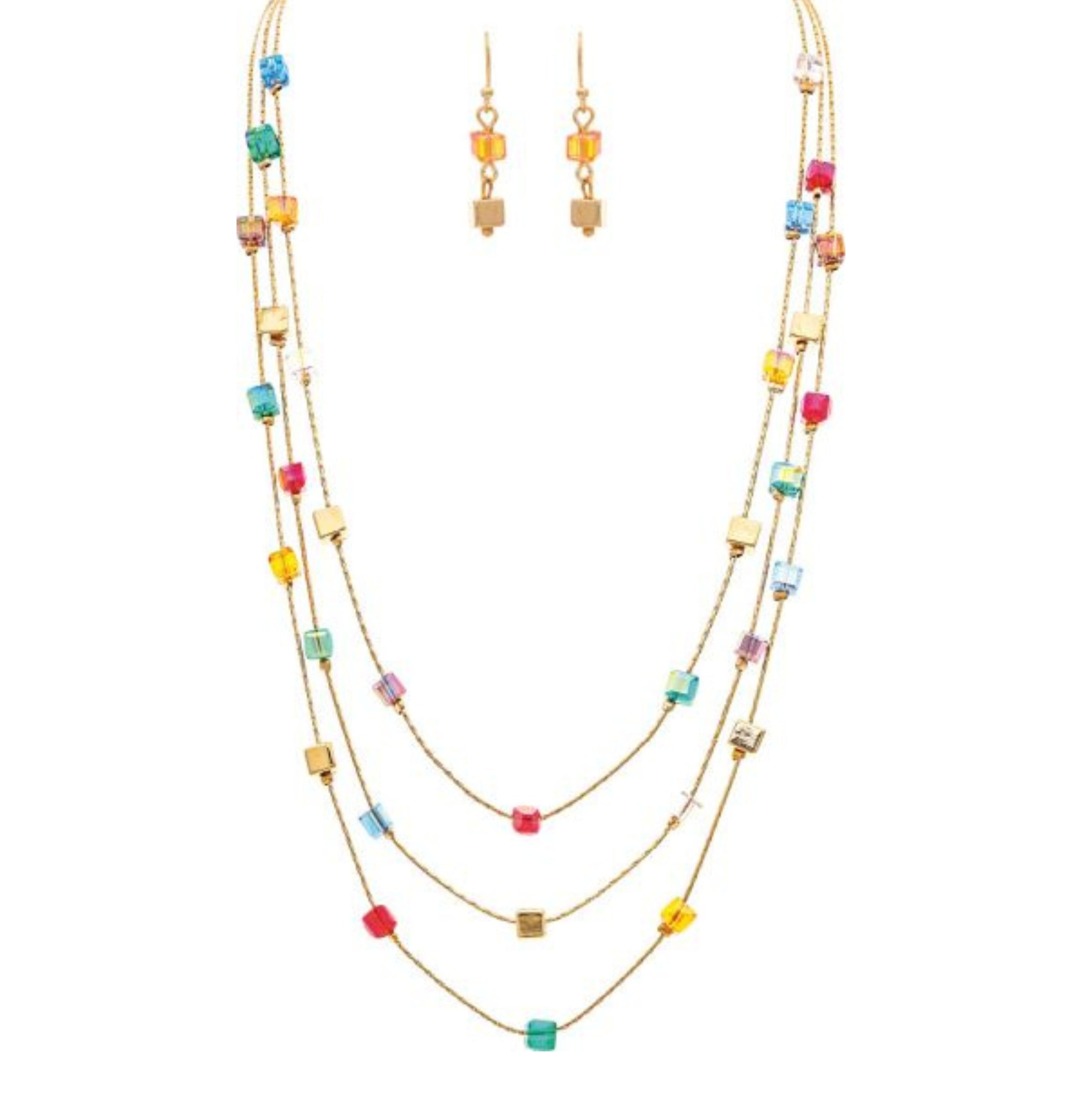 The A-Train Gold Aurora Borealis Coated Multicolor Cube Bead Layer Necklace Set features three layers with red, blue, green, yellow, and pink cube beads and matching gold earrings with small yellow square beads. Displayed on a white background.