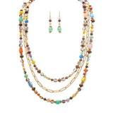 The A-Train Gold Multicolor Faceted Square Beads Layer Necklace Set features high-quality mixed metal craftsmanship and includes matching green beaded dangle earrings for a coordinated look.