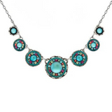 Adorned with five round pendants, each showcasing a vibrant turquoise center and accented with splashes of pink, green, and yellow, the Kensington Circles Bermuda Blue Necklace by Firefly is a stunning piece of handmade jewelry. Arranged symmetrically on a delicate silver chain, this fair-trade accessory captures vibrant elegance in every detail—perfect for anyone who appreciates unique craftsmanship from Firefly Jewelry.