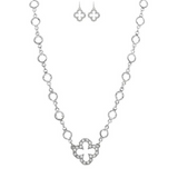 The A-Train Silver Crystal By The Inch Clover Charm Necklace Set features a necklace with a cross-shaped pendant and matching earrings, both adorned with sparkling crystals and circular links for an elegant, coordinated look.