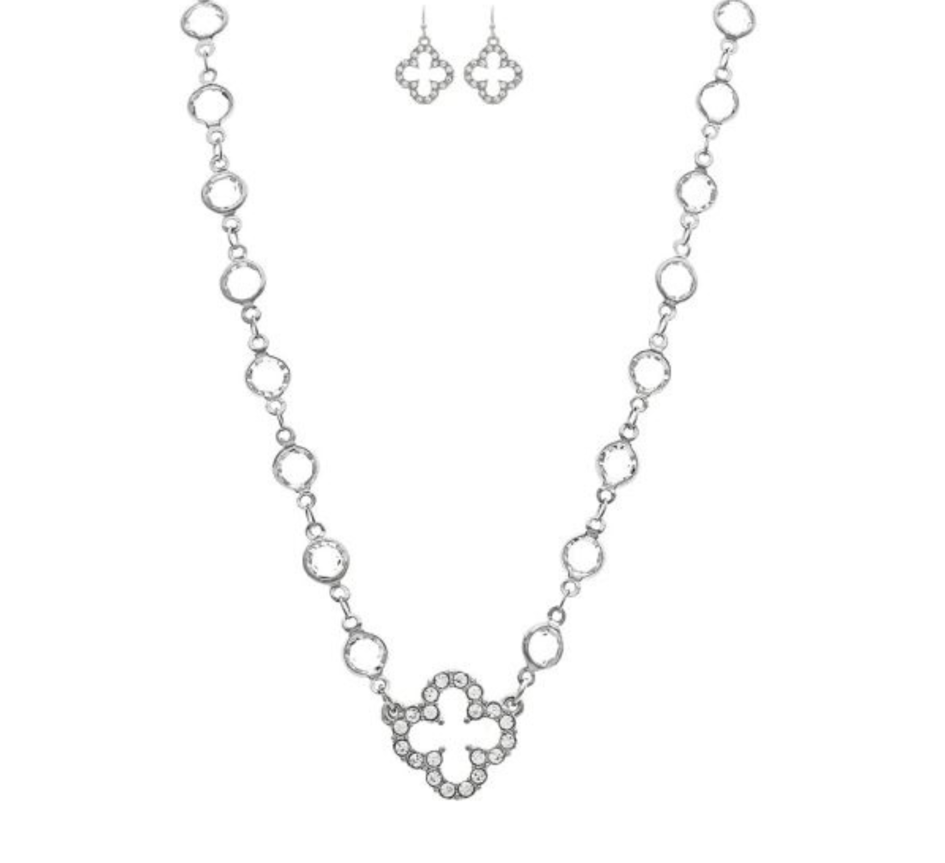 The A-Train Silver Crystal By The Inch Clover Charm Necklace Set features a necklace with a cross-shaped pendant and matching earrings, both adorned with sparkling crystals and circular links for an elegant, coordinated look.