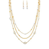 The A-Train Gold White Flowers Beads Chain Layer Necklace Set features a chic necklace and matching drop earrings with delicate chains, pearls, and beads—timelessly styled and perfectly showcased on a plain white background.