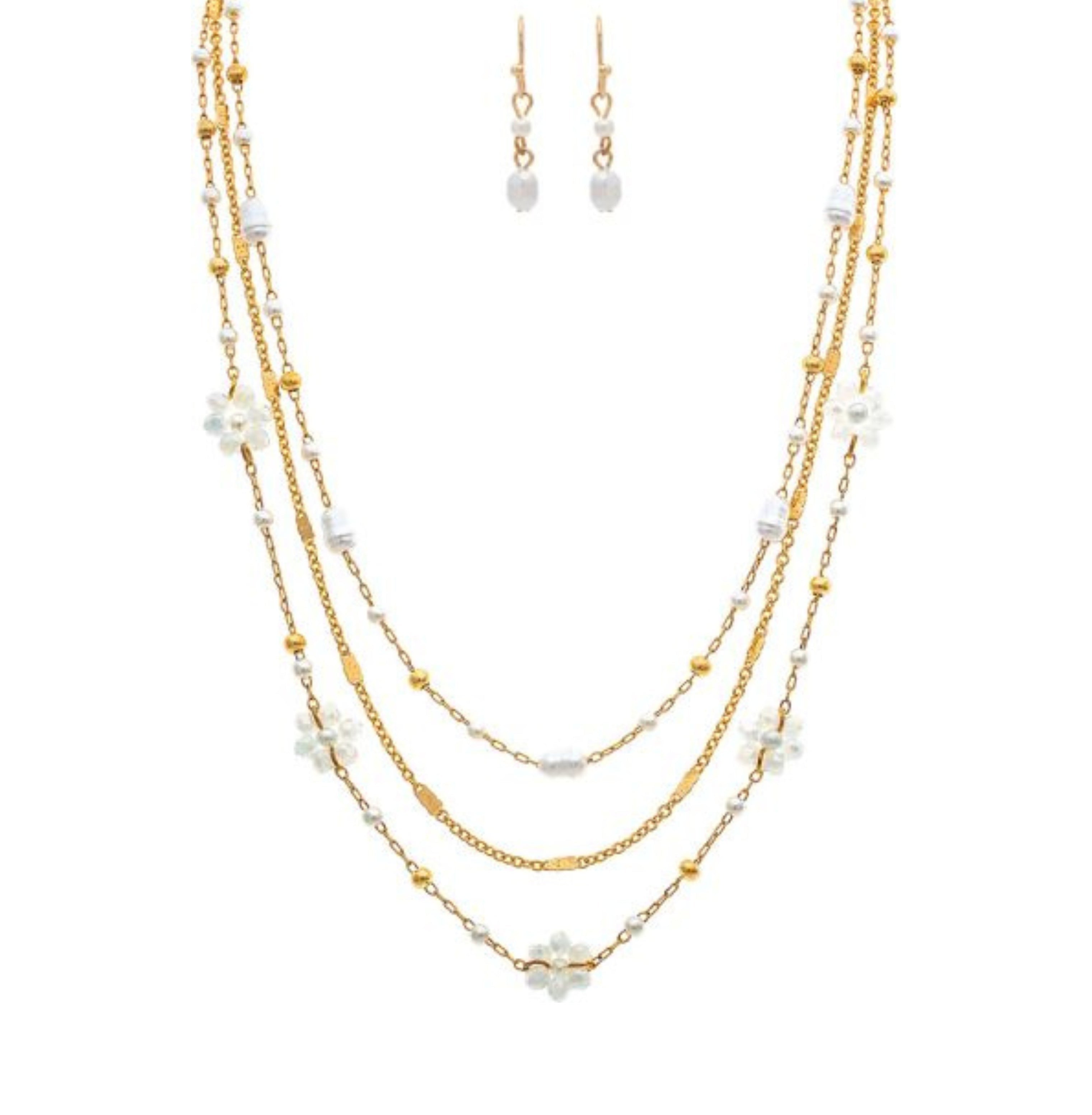 The A-Train Gold White Flowers Beads Chain Layer Necklace Set features a chic necklace and matching drop earrings with delicate chains, pearls, and beads—timelessly styled and perfectly showcased on a plain white background.
