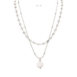 The A-Train Silver Layer Chain FWP Coin Drop Necklace Set features layered silver chains, a round pearl pendant, and matching pearl earrings, all displayed on a white background for an elegant look.