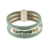 The Origin Matte Silver & Aqua Magnetic Bracelet features three teal leather bands, a silver clasp, and a central row of turquoise glass beads with metallic cube and matte silver accents.