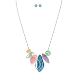 The A-Train Silver Multi-Color Pastel Organic Shapes Necklace Set features a stylish abstract pendant with matching blue stud earrings, crafted from high-quality mixed jeweler’s metals and displayed on a white background.