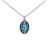 The Single Mosaic Oval Pendant Aqua Necklace by Firefly showcases an oval-shaped blue gemstone adorned with smaller light blue stones and a decorative border—an exquisite piece from Firefly’s jewelry collection.