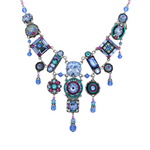 The La Dolce Vita Bib Light Blue Necklace by Firefly features geometric shapes in light blue with intricate patterns and crystals on a silver chain, showcasing stunning fair-trade craftsmanship.