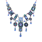 The La Dolce Vita Bib Light Blue Necklace by Firefly features geometric shapes in light blue with intricate patterns and crystals on a silver chain, showcasing stunning fair-trade craftsmanship.