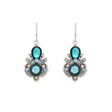 A pair of ornate silver earrings featuring light blue oval and round gemstones, intricate scrollwork, and dangling hooks are displayed on a white background. These Moonlight Exclamation Point Fancy Light Blue Earrings by Firefly Jewelry highlight the brand’s artistry and handcrafted appeal from Guatemala, making a unique addition to any jewelry collection.