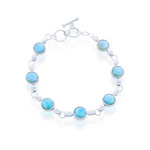 The Classic of New York Larimar Round Bezel Set Links Toggle Bracelet features seven round blue larimar stones set in sterling silver along a delicate chain with a toggle clasp, shown on a white background.