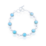 The Classic of New York Larimar Round Bezel Set Links Toggle Bracelet features seven round blue larimar stones set in sterling silver along a delicate chain with a toggle clasp, shown on a white background.