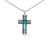 The Moonlight Medium Cross Light Blue Necklace by Firefly features a silver chain with a cross pendant adorned with turquoise and clear gemstones in a geometric pattern, highlighting the exquisite handmade craftsmanship of Firefly Jewelry.