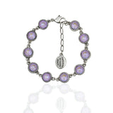 The 10 Simple Drops Lavender Bracelet by Anne Koplik Designs, Inc. features round purple gemstones in beaded settings, linked together with an adjustable chain, lobster clasp, and an oval tag engraved with the brand name.