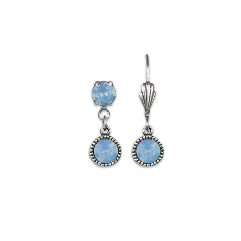 The Simple Drop Air Blue Opal Earrings by Anne Koplik Designs, Inc. are silver earrings with two round light blue gemstones each and decorative metalwork. One earring is shown from the front, the other from the side on a white background.