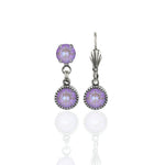 Simple Drop Lavender Earrings by Anne Koplik Designs, Inc. feature a timeless silver drop style with two round faceted lavender stones set in ornate bezels, reflected on a white background.