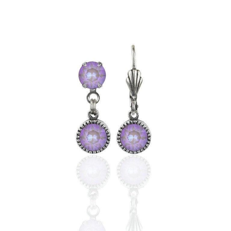 Simple Drop Lavender Earrings by Anne Koplik Designs, Inc. feature a timeless silver drop style with two round faceted lavender stones set in ornate bezels, reflected on a white background.