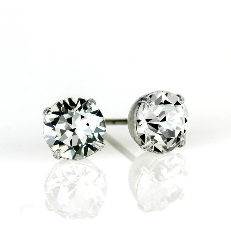 Anne Koplik Designs, Inc. Simple Post Crystal Earrings feature round, faceted crystals in a four-prong white metal setting—an elegant choice for bridesmaid jewelry, shown on a white reflective surface.