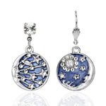 The Enamel & Stone 1 Moon/1 Star Earrings by Anne Koplik Designs, Inc. feature silver drop earrings with galaxy-inspired blue enamel pendants—one with stars and planets, the other with a sun and moon—each topped with a sparkling stud.