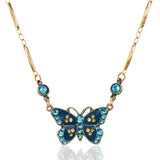 The Enamel & Stone Teal Butterfly Necklace by Anne Koplik Designs, Inc. features a butterfly pendant with blue and yellow stones and two round blue crystals on a decorative gold chain—a refined crystal-embellished accessory.