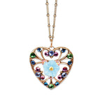 The Filigree & Stone Heart/Flower Necklace by Anne Koplik Designs, Inc. features a handmade gold heart filigree, multicolored gemstones, and a central blue flower pendant on a delicate gold chain.