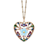 The Filigree & Stone Heart/Flower Necklace by Anne Koplik Designs, Inc. features a handmade gold heart filigree, multicolored gemstones, and a central blue flower pendant on a delicate gold chain.