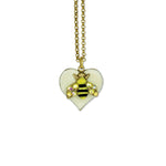 The Whimsy Heart/Bumble Bee Necklace by Anne Koplik Designs, Inc. features a gold chain with a white crystal heart pendant and a bee charm embellished with sparkling gems on its wings.