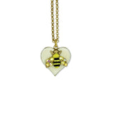 The Whimsy Heart/Bumble Bee Necklace by Anne Koplik Designs, Inc. features a gold chain with a white crystal heart pendant and a bee charm embellished with sparkling gems on its wings.