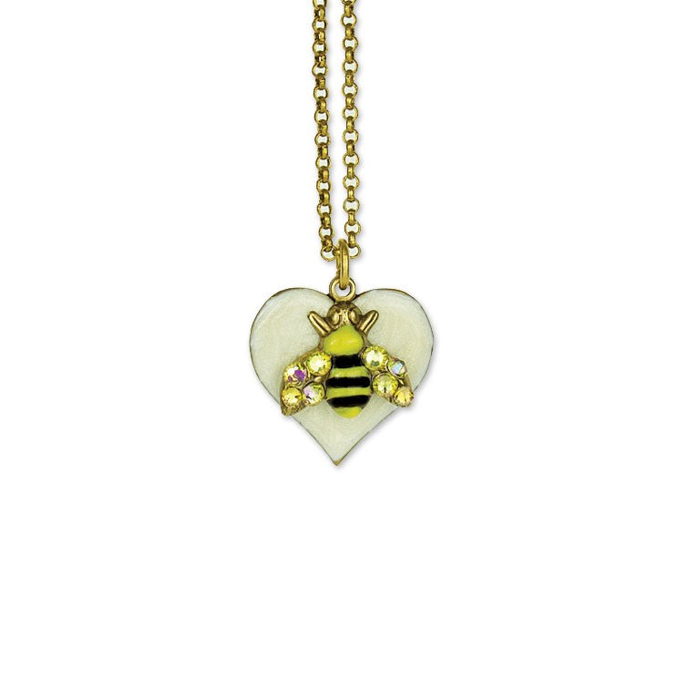 The Whimsy Heart/Bumble Bee Necklace by Anne Koplik Designs, Inc. features a gold chain with a white crystal heart pendant and a bee charm embellished with sparkling gems on its wings.