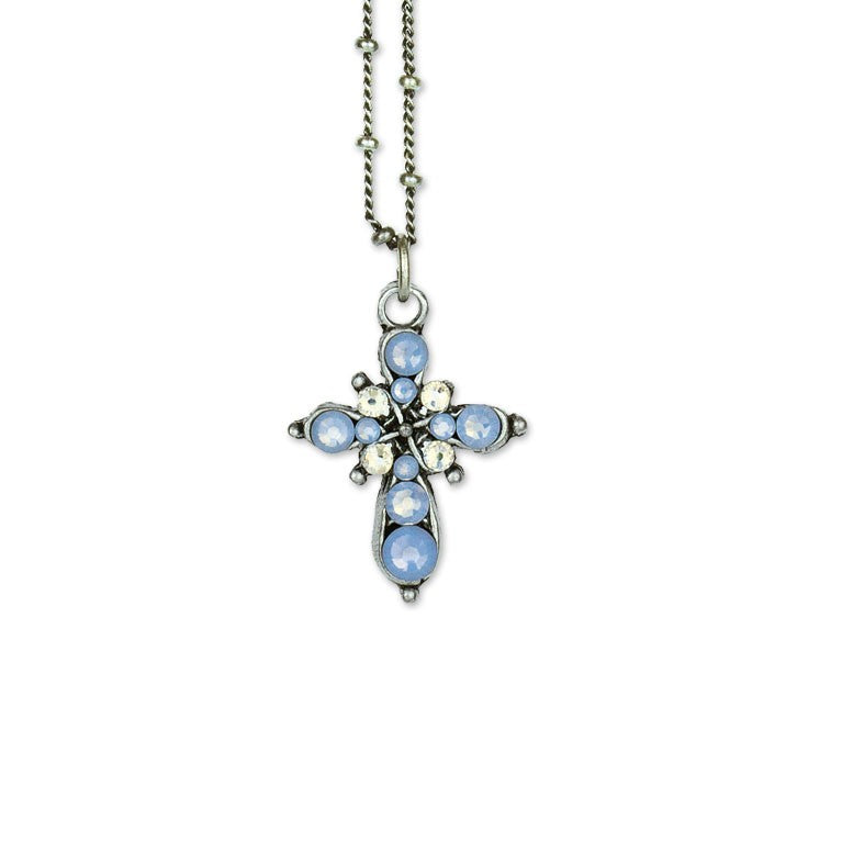 The Anne Koplik Designs, Inc. Small Stone Fancy Cross Light Blue Necklace features clusters of blue and white stones with crystal accents on a delicate silver chain, shown against a white background.