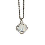The Simple Clover/Faceted Stone White Opal Necklace by Anne Koplik Designs, Inc. features a vintage-inspired, silver-plated design with a dark twisted chain and a round opalescent pendant adorned with iridescent stones.