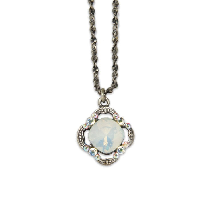 The Simple Clover/Faceted Stone White Opal Necklace by Anne Koplik Designs, Inc. features a vintage-inspired, silver-plated design with a dark twisted chain and a round opalescent pendant adorned with iridescent stones.