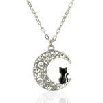 The Crescent Moon w/Black Cat Necklace by Anne Koplik Designs, Inc. features a crescent pendant with ornate swirls, sparkling crystals, and a black cat elegantly perched inside.