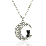 The Crescent Moon w/Black Cat Necklace by Anne Koplik Designs, Inc. features a crescent pendant with ornate swirls, sparkling crystals, and a black cat elegantly perched inside.