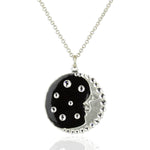The Black & Crystal Crescent Moon Face w/Stars Necklace by Anne Koplik Designs, Inc. features a silver-plated brass round pendant with a crescent moon face, black enamel, sparkling rhinestones, and celestial crystal accents.