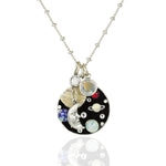 The Jumble of Planets and Moon Necklace by Anne Koplik Designs, Inc. features a circular pendant with a Man in the Moon charm, colorful planet accents, and crystals—a miniature solar system on a silver chain.