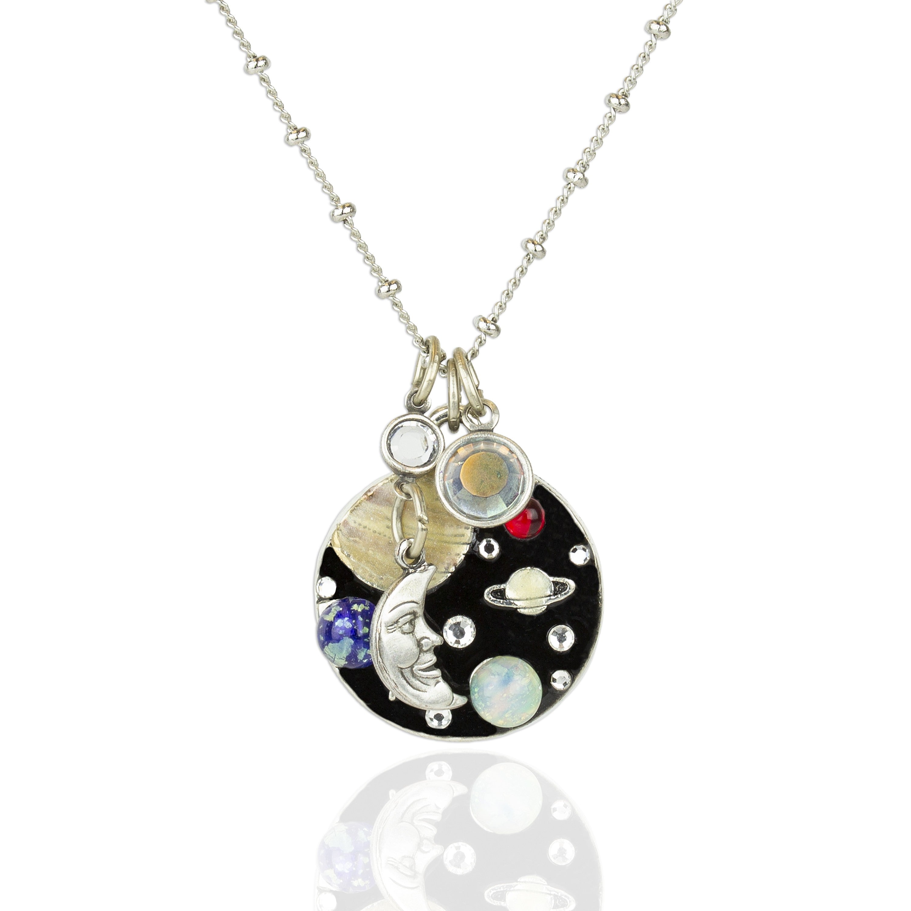 The Jumble of Planets and Moon Necklace by Anne Koplik Designs, Inc. features a circular pendant with a Man in the Moon charm, colorful planet accents, and crystals—a miniature solar system on a silver chain.
